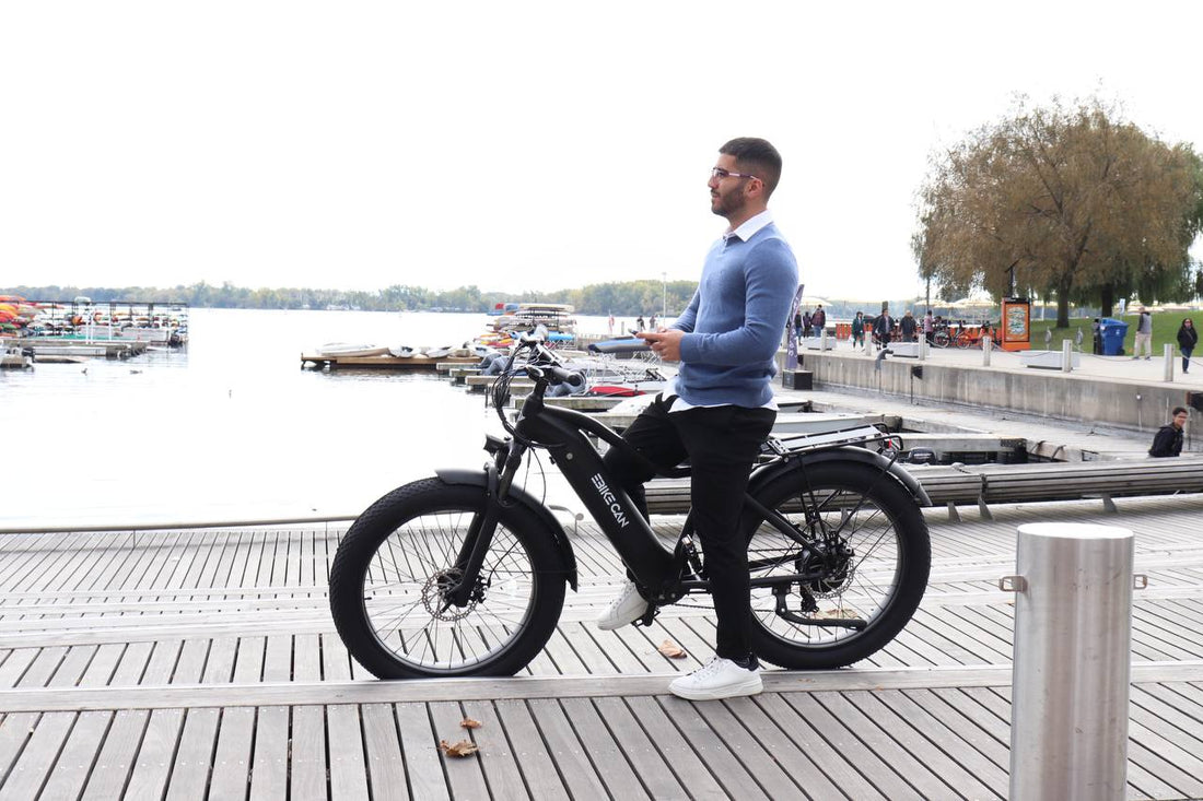 a man in blue sweater sitting on a ebike next to the Ontario lake